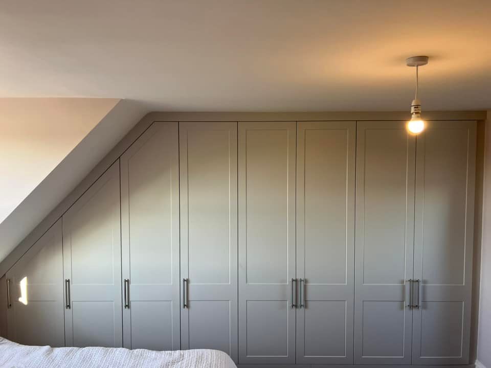 Bedroom with built-in wardrobes and a single hanging light bulb.